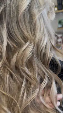 Balayage blond sur cheveux longs ondulés réalisé au Salon de S